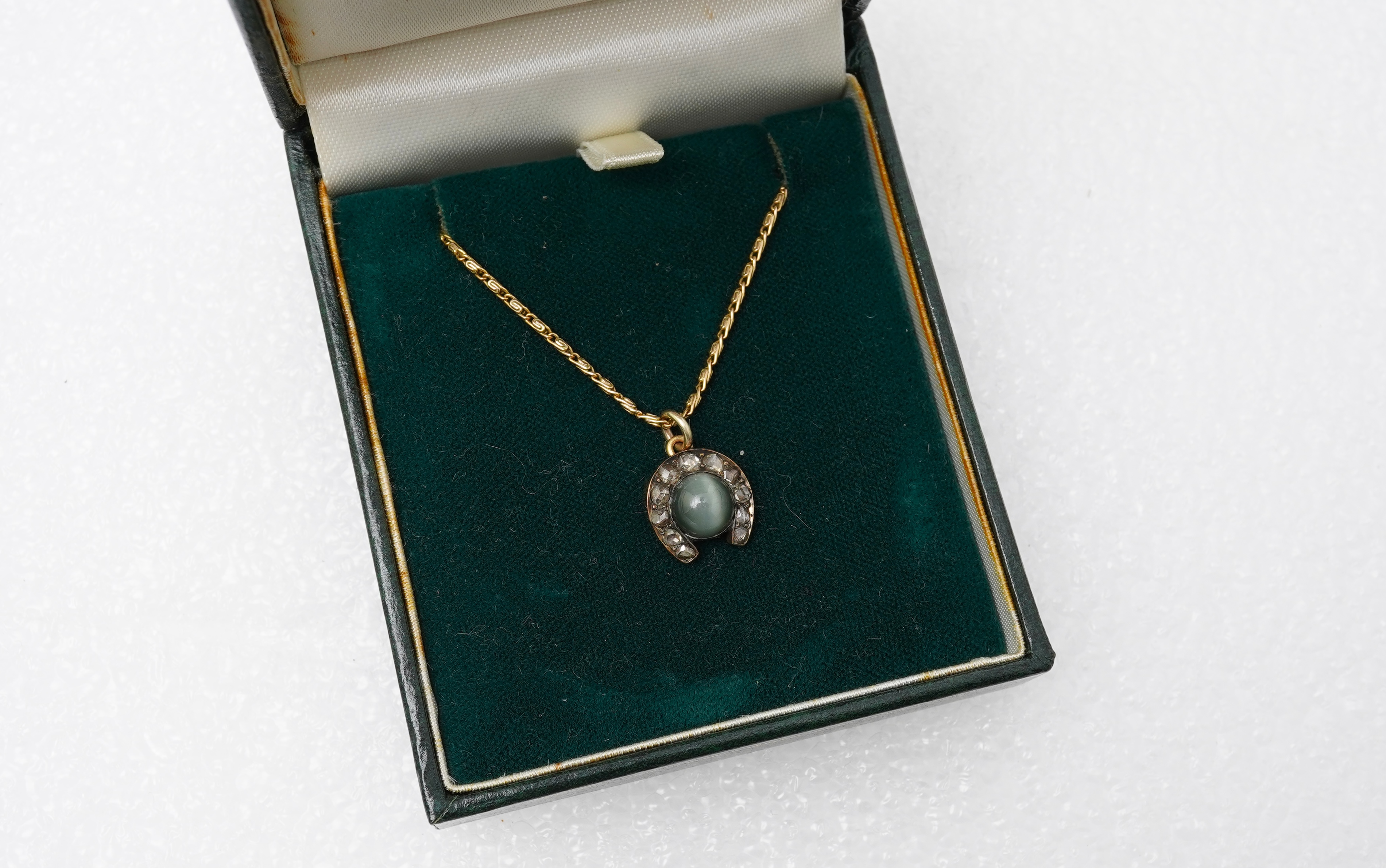 A yellow metal, cat's eye quartz and rose cut diamond cluster set horseshoe pendent, 11mm, together with a 9ct gold chain, 41cm, gross weight 5 grams.